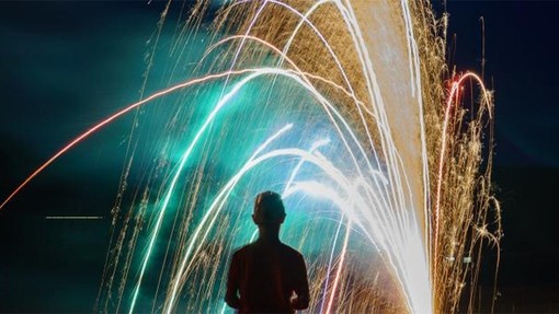 A person stood in front of a firework display